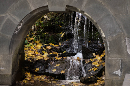 一条小瀑布穿过树叶穿过拱门图片