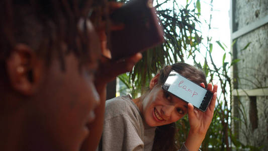 Friends sit in a cafe, man and woman play in word game with phon