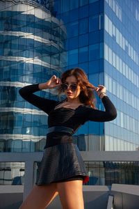 年轻富于表情的女人站在蓝色摩天大楼的背景上。城市时尚理念，软聚焦