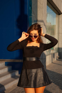 年轻富于表现力的女人站在蓝色城市建筑的背景上。城市时尚理念，软聚焦