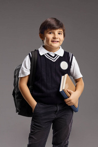 Boy in a school uniform holding books and smiling 