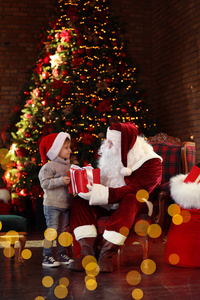 圣诞老人在圣诞树附近给小男孩礼物