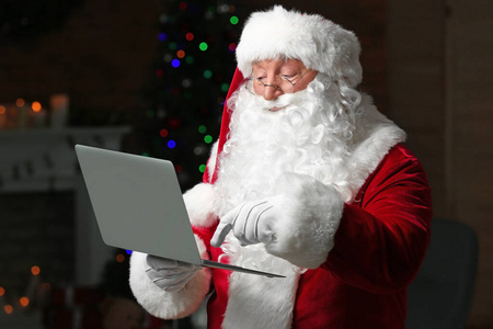 圣诞老人在房间里用笔记本电脑装饰圣诞