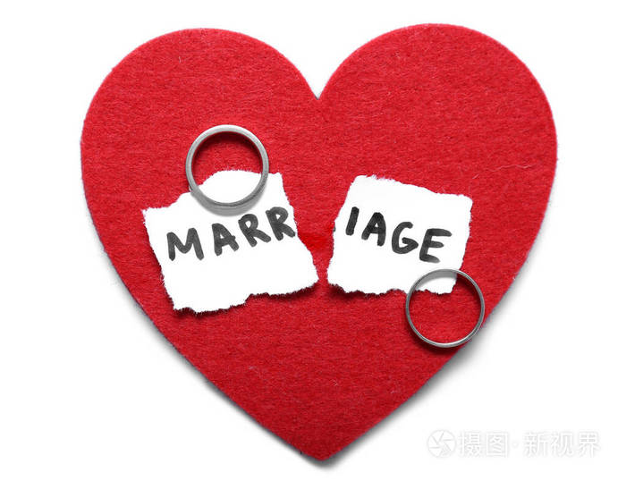 红色的心撕碎的纸上写着婚姻一词还有浅背景上的戒指离婚的概念