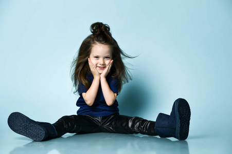 穿着t恤，皮裤和深蓝色ugg靴子的可爱小女孩在地板上摆姿势