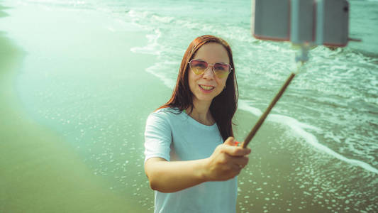 快乐的女人在海边自拍。从上面高兴的女人用