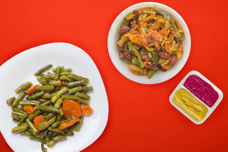  Green beans with garlic carrots on a white plate on a colored b