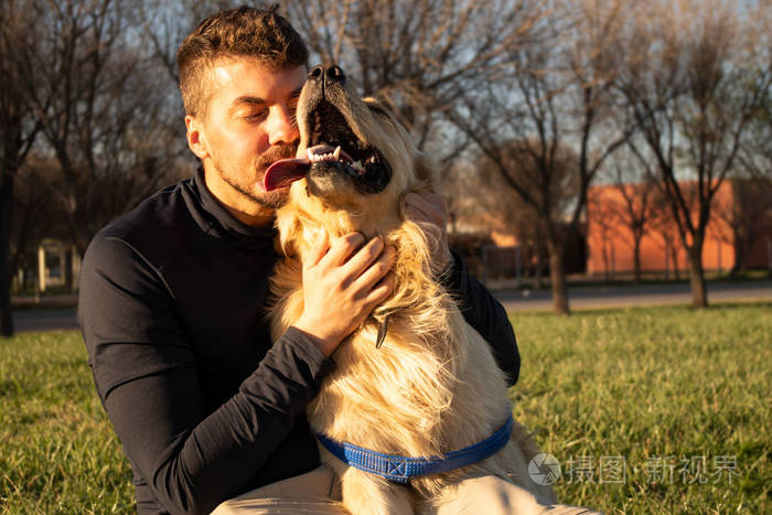 一个男人抱着他的宠物一只金色的猎犬他们看起来很高兴