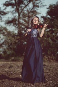 一张美丽女孩的脸，下巴下托着小提琴，年轻女子在孤独中演奏着大自然的乐器，感受着音乐和情感