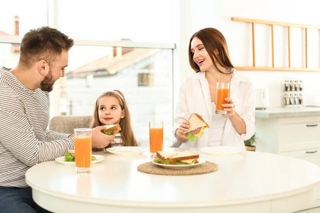 快乐的一家人在厨房里吃早餐和三明治