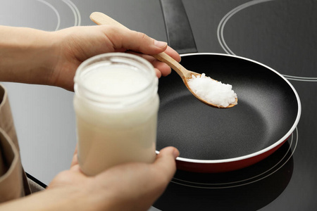 女人在感应炉上用椰子油烹饪,特写照片