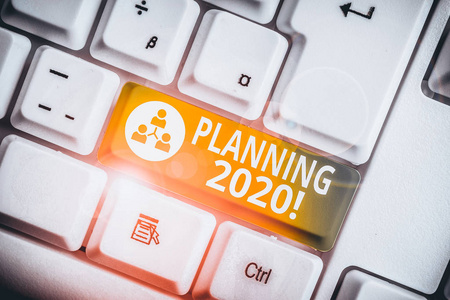 写下2020年规划的笔记。商业照片展示了明年计划的过程白色电脑键盘，白色背景上有便笺。