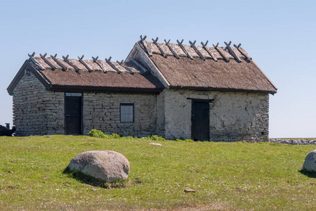 在瑞典的房子一座古老的石头房子矗立在绿色的草地上.瑞典奥兰照片