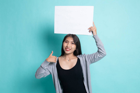 年轻的亚洲女人竖起大拇指，手上挂着白色的空白符号。