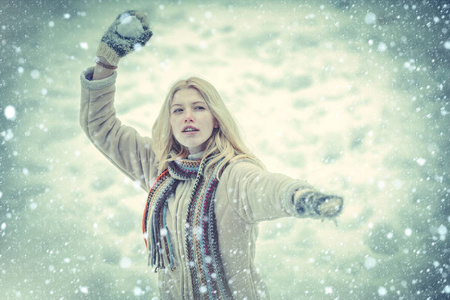 可爱俏皮的年轻女子在户外享受初雪。寒假里玩雪球的女孩。