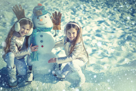 冬天雪蓝色调。孩子们在白雪的背景上堆雪人。快乐的孩子们在雪地里和雪人玩耍。