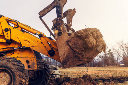 斗式拖拉机一台大型斗式挖掘机挖掘地面铺设道路的特写.照片