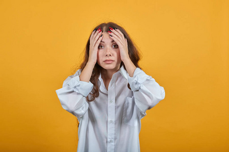 害怕的白人年轻女子双手抱头,看着镜头,迷茫照片