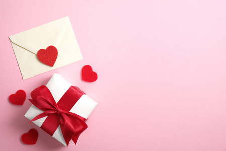 浪漫的情书和礼品盒，粉红色背景上有红色丝带，还有情人节的心形图案。平面布置，俯视图，复印空间。情人节快乐概念