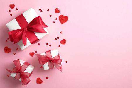 礼品盒包装白纸，红色丝带蝴蝶结和粉色背景上的情人节心形图案。平放，俯视图。情人节或母亲节的横幅或贺卡模型。