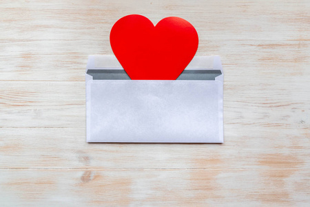 木制背景上的情人节红心信封。情书符号。