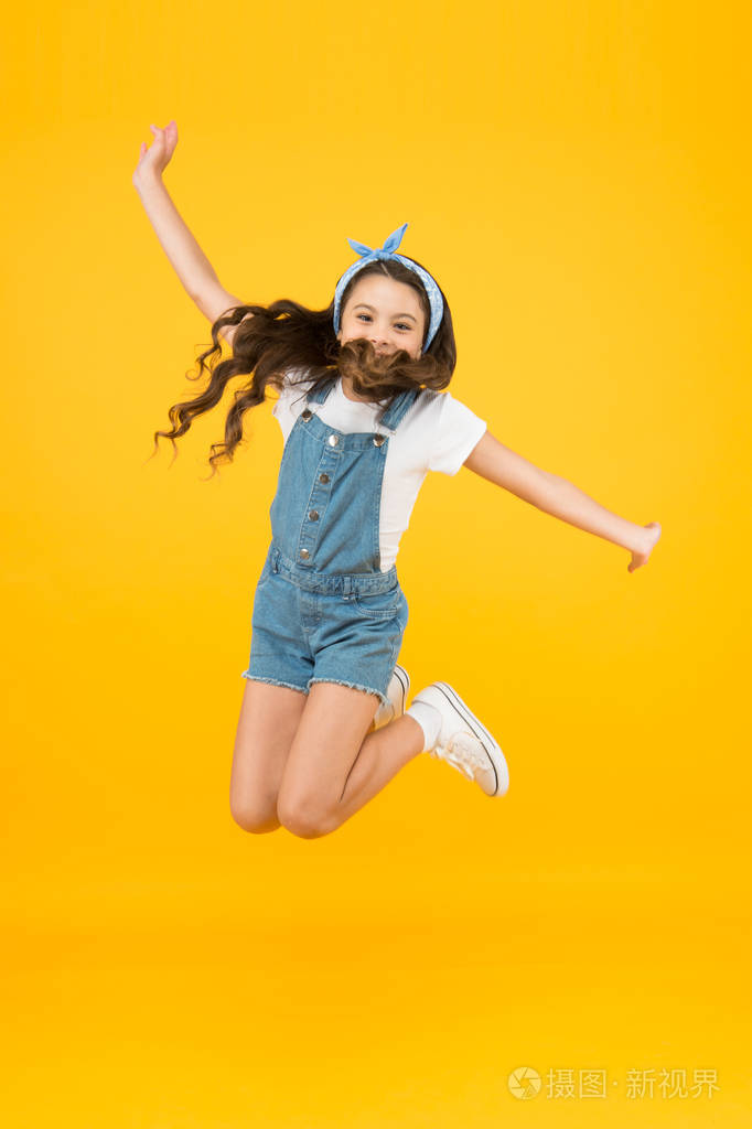 娱乐和放松.感觉自由.无忧无虑的孩子.暑假.快乐的跳跃.小女孩跳黄底.