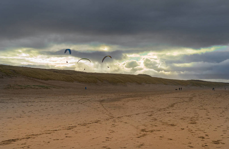 三个滑翔伞在海滩上空的地平线上飞过