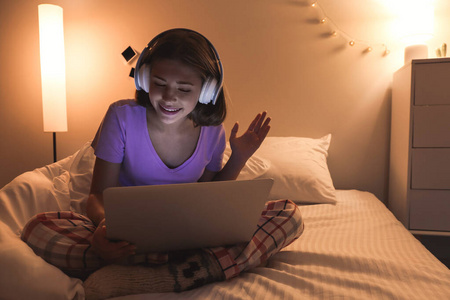 晚上带着笔记本电脑在卧室听音乐的少女照片