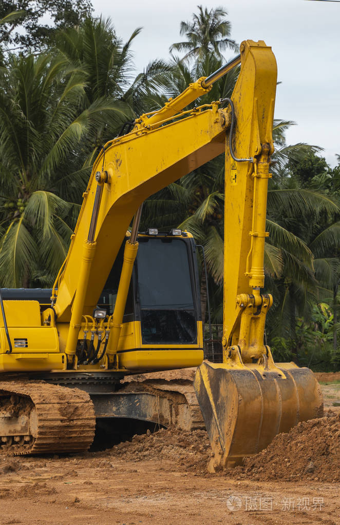 一个橙色的大背景挖掘机站在地上.