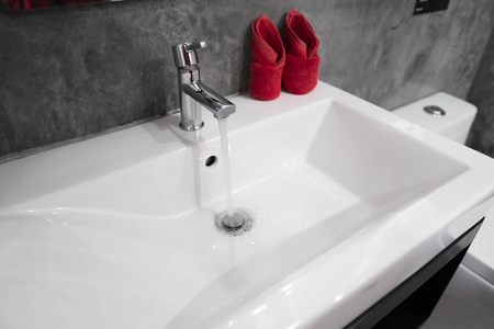 自来水从现代不锈钢水龙头在白色水槽。柜台浴室内部现代。豪华时尚设计浴室，墙面采用混凝土风格。