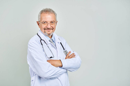 开朗成熟的医生面对镜头医疗保健和药品摆姿势微笑。