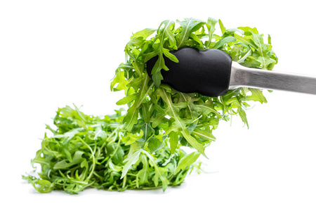 Tongs with rocket salad leaves isolated on white 