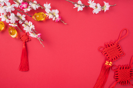 中国农历新年的设计理念美丽的中国结与梅花孤立在红色背景，平放，俯视，布局。