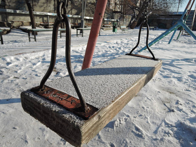 Empty swing in winter time with snow