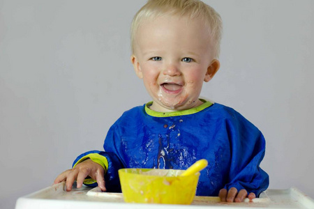 Cute baby in laundry basket in front of washing machine. 