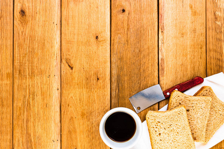 Cup of coffee and wholegrain toast over wooden table, top view, 