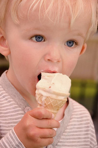 Closeupportrait of cute blond boy who licks icecream. 