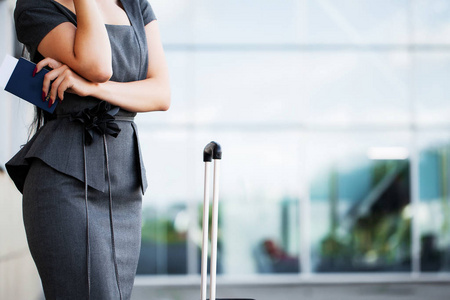 旅行。机场女商务人员拿着手提行李在机场登机口边用智能手机聊天