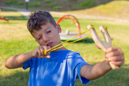 小男孩在操场用弹弓射击照片