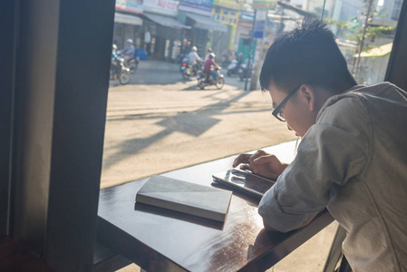 亚洲男人在阳光明媚的早晨使用平板电脑