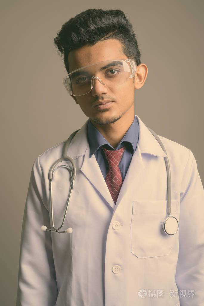 年轻的印度医生戴着灰色背景的护目镜