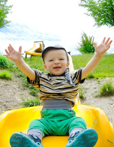 Happy toddler sliding down a long slide in the nature. 