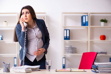 在办公室工作的年轻孕妇照片