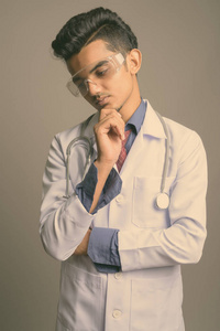 年轻的印度医生戴着灰色背景的护目镜