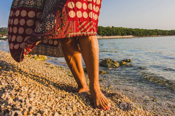 清晨一个赤脚女人在海边的石头上行走