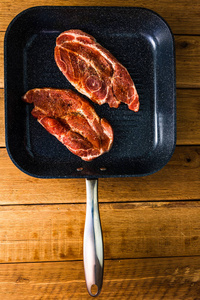 Pork chops with condiments and smoked sausage on a black frying 