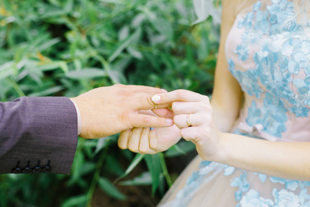 新娘给新郎戴了一枚戒指。婚礼上手指上戴着戒指的新婚夫妇白天。婚礼仪式特写镜头。