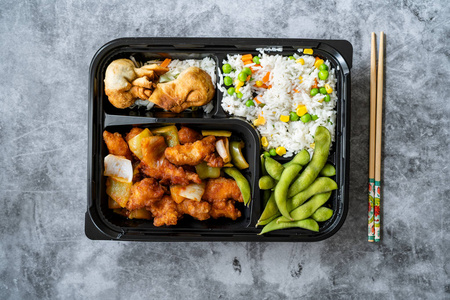 外卖日本食品便当盒菜单,包括鸡肉,油炸饺子,毛豆和蔬菜饭,包装在塑料