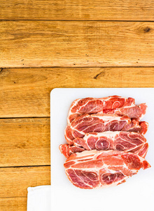 Pork chops on a white cutting board over wooden table, meat for 