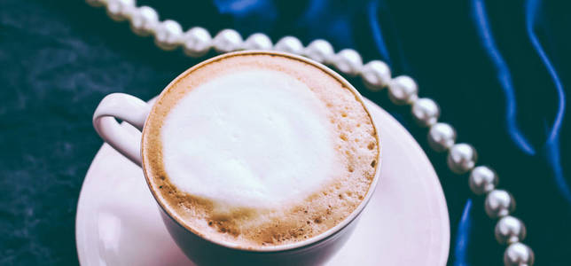 Cup of cappuccino for breakfast with satin and pearls jewellery 
